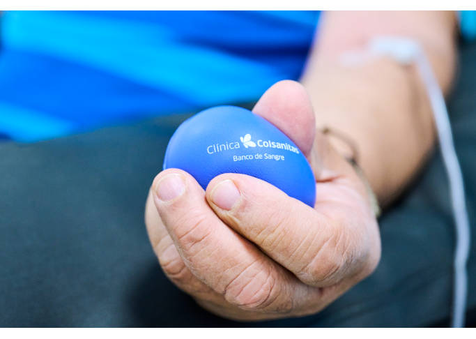 En un primer plano se ve una mano apretando una pelota antiestrés con el logo de Clínica Colsanitas.