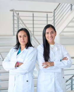  Se ve a 2 profesionales de la salud usando bata blanca sonriendo y de fondo se puede ver una escalera, se puede inferir que el lugar corresponde a...