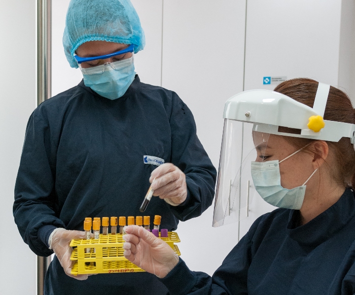 Dos profesionales de la salud se encuentran vestidos con ropa quirurgica y mascara protectora, 
