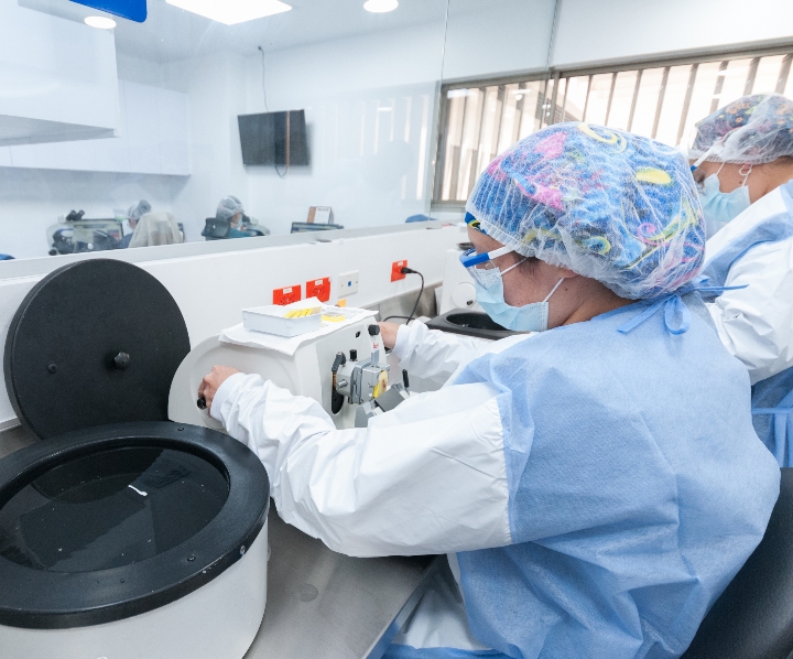 Una doctora se encuentra sentada frente a equipos médicos analizando muestras de laboratorio