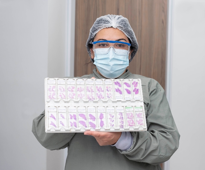 Una profesional de la salud vestida con bata, gorro y tapabocas se encuentra sosteniendo un documento educativo